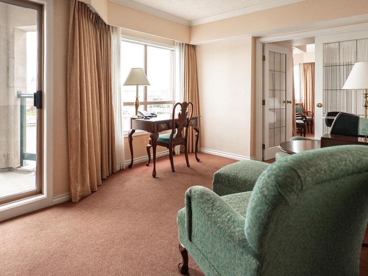 Guest suite with green armchairs and private balcony