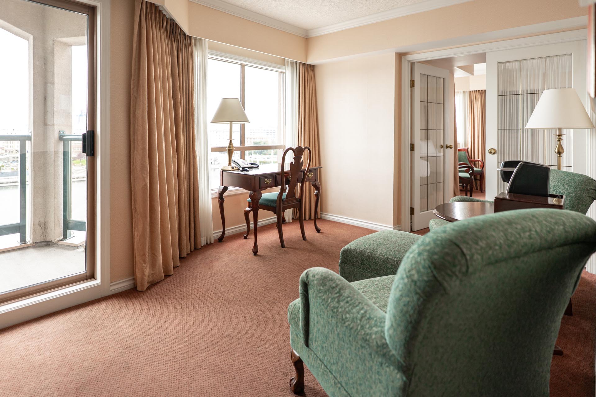 Guest suite with green armchairs and private balcony