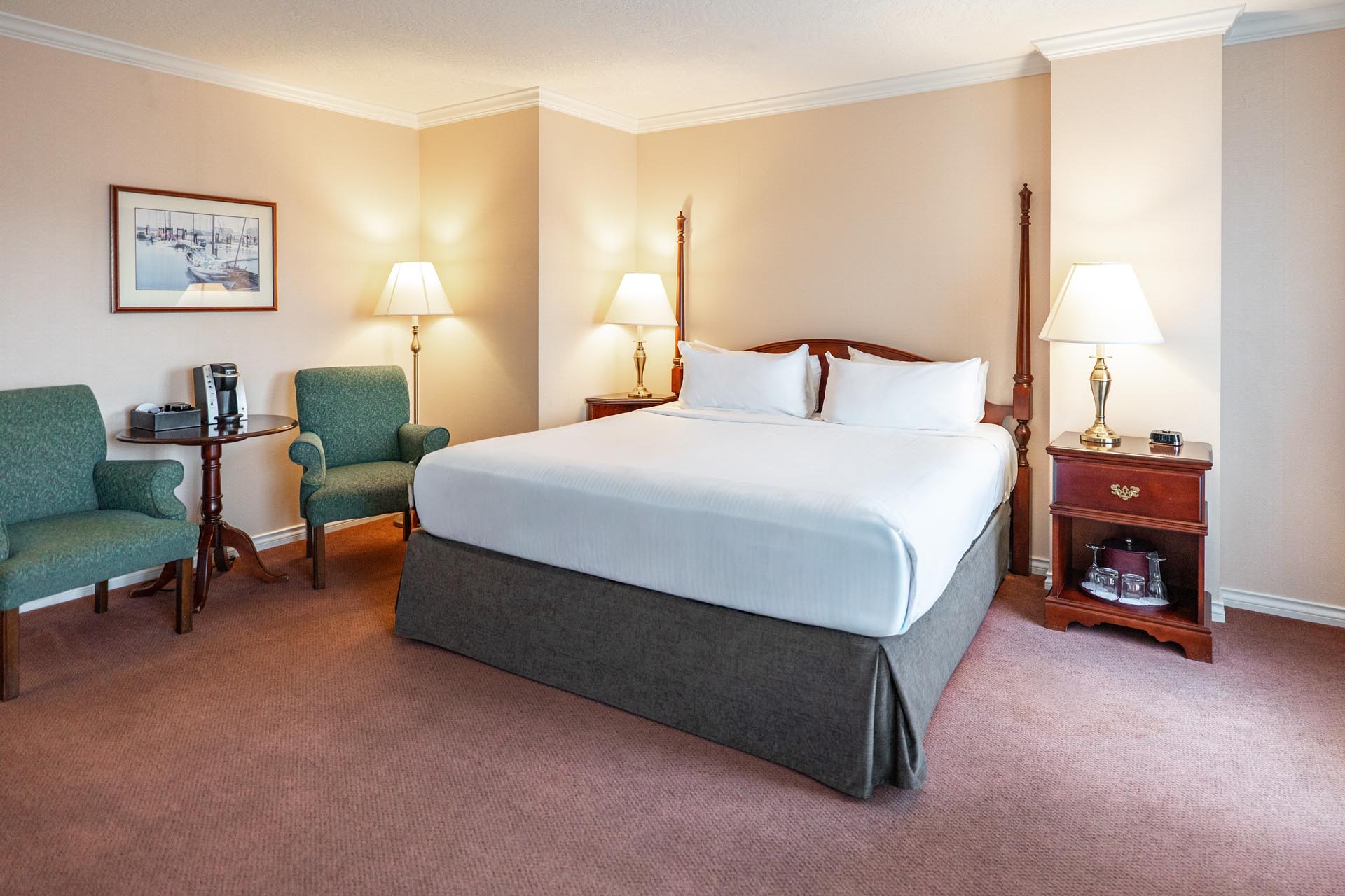 King bed beside green armchairs